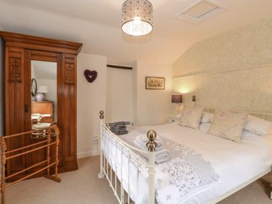 A bedroom with a bed towels a wooden wardrobe and a lamp at Cosy Cottage in Bawdeswell