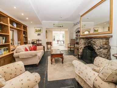 A living room with sofas a wooden coffee table a stone fireplace and bookshelves at Valley View in Dalton-In-Furness