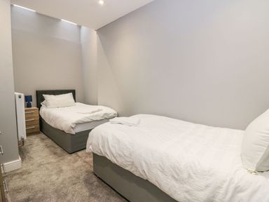 A bedroom with two single beds bedside table and lamp at Valley View in Dalton-In-Furness