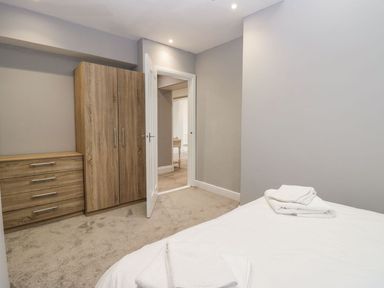 A bedroom with a bed towels a wooden wardrobe and dresser at Valley View in Dalton-In-Furness