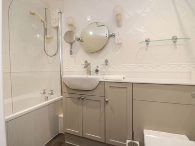A bathroom with a bathtub shower combination a sink with a cabinet and two mirrors at Valley View in Dalton-In-Furness