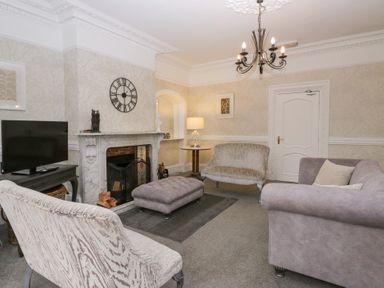 A living room with sofas a fireplace a television and a chandelier at Valley View in Dalton-In-Furness