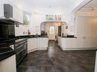 A kitchen with black countertops white cabinets a stove and a refrigerator at Valley View in Dalton-In-Furness