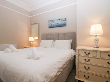 A bedroom with a double bed two bedside tables with lamps a chest of drawers and a painting on the wall at Valley View in Dalton-In-Furness