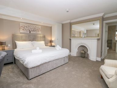 A bedroom with a large bed bedside tables a fireplace and an armchair at Valley View in Dalton-In-Furness