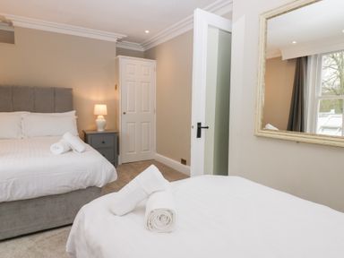 A bedroom with two beds rolled towels on the beds a bedside table with lamp and a large mirror on the wall at Valley View in Dalton-In-Furness