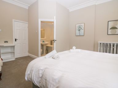 A bedroom with a double bed with towels on it two doors on one wall and framed pictures on another wall at Valley View in Dalton-In-Furness
