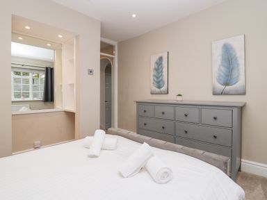 A bedroom with a bed and rolled towels a grey dresser with two paintings above it at Valley View in Dalton-In-Furness