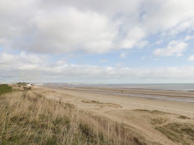 A sandy beach with grass in the foreground and a cloudy sky at Bridlington Bay House in Bridlington