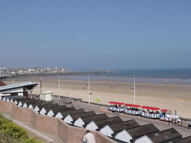 A beach with a promenade and a small tourist train on the track at Bridlington Bay House in Bridlington