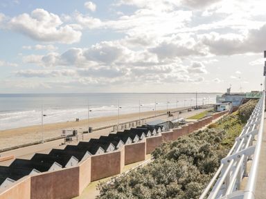 A beach with a promenade and small black-roofed huts near the sea at Bridlington Bay House in Bridlington