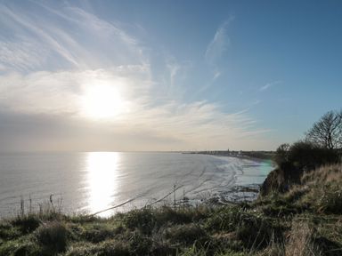 A coastal cliff overlooking the sea with a town in the distance at Bridlington Bay House in Bridlington