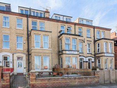 A row of brick residential buildings with multiple windows and small fenced front gardens at Bridlington Bay House in Bridlington