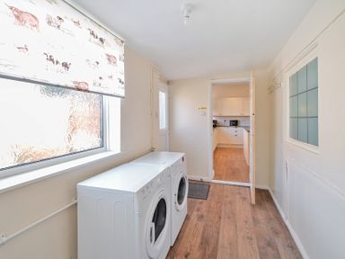 A laundry room with washing machine and dryer next to a window with animal print blind at Bridlington Bay House in Bridlington