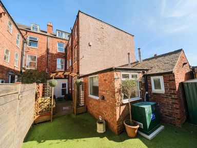 An outdoor area with brick buildings wooden fences greenery and potted plants at Bridlington Bay House in Bridlington