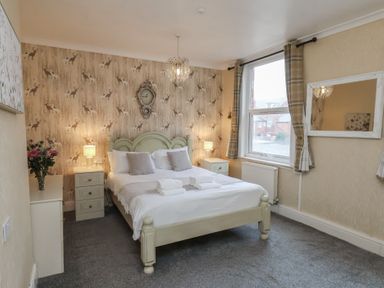 A bedroom with a bed, nightstand, and window at Bridlington Bay House in Bridlington