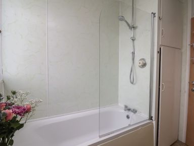 A bathroom with a shower over a bathtub and a flower bouquet at Bridlington Bay House in Bridlington