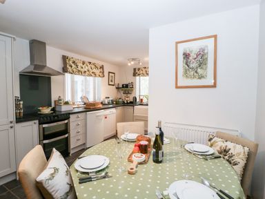 A kitchen with a dining table set for four and kitchen appliances at Little Stables Cottage in Spetisbury