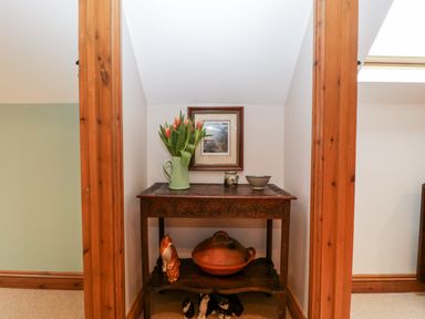 A wooden table with flowers in a green jug a framed picture and pottery in a small alcove at Little Stables Cottage in Spetisbury