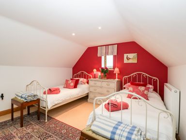A bedroom with two single beds a chest of drawers and a small window at Little Stables Cottage in Spetisbury