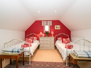 A bedroom with two single beds a chest of drawers a window and bedside lamps at Little Stables Cottage in Spetisbury