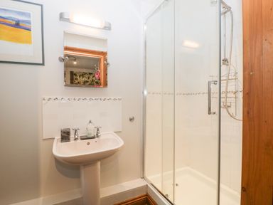 A bathroom with a sink mirror and shower enclosure at Little Stables Cottage in Spetisbury