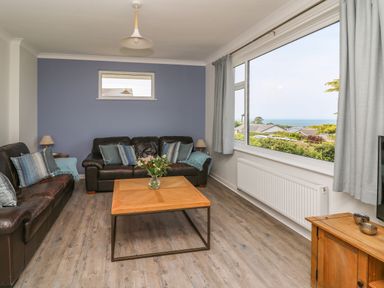 A living room with two leather sofas a wooden coffee table and a large window showing a sea view at Bryn Alaw in Newport Pembrokeshire