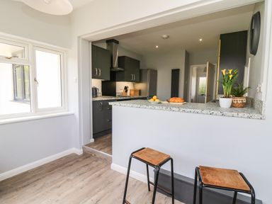 A kitchen with dark cabinets and a counter with stools and plants at Bryn Alaw in Newport Pembrokeshire