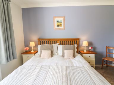 A bedroom with a wooden bed and two bedside tables with lamps and flowers at Bryn Alaw in Newport Pembrokeshire