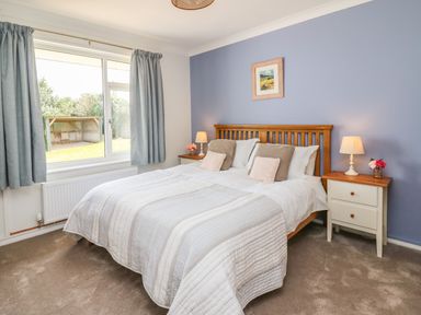 A bedroom with a double bed two bedside tables with lamps and a window with curtains at Bryn Alaw in Newport Pembrokeshire