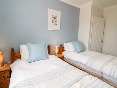 A bedroom with two single beds with blue pillows and striped blankets at Bryn Alaw in Newport Pembrokeshire