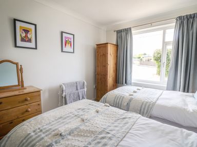 A bedroom with two single beds a wooden wardrobe and a wooden dresser with a mirror at Bryn Alaw in Newport Pembrokeshire