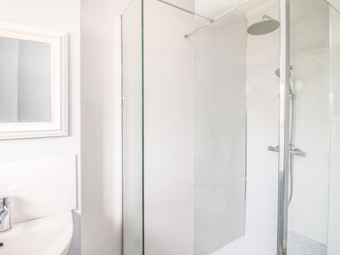 A bathroom with a shower enclosure and a sink with a faucet and mirror at Bryn Alaw Newport Pembrokeshire