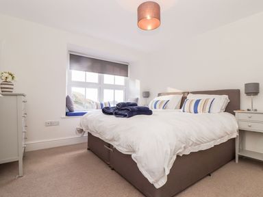 A bedroom with a double bed with white bedding and striped pillows at Cliffside Trebarwith Strand near Tintagel