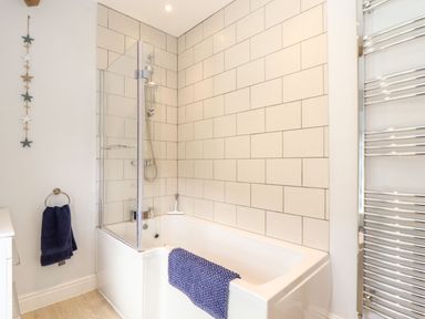 A bathroom with a bathtub a shower a glass shower screen and towel racks at Cliffside Trebarwith Strand near Tintagel