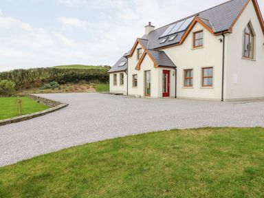 A house with a gravel driveway and grass lawn at Ballycahane in Castletownshend County Cork