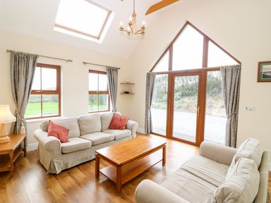 A living room with two sofas a wooden coffee table and large windows at Ballycahane in Castletownshend County Cork