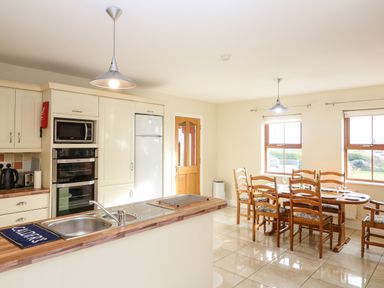 A kitchen with sink countertop oven microwave dining table and chairs at Ballycahane in Castletownshend County Cork