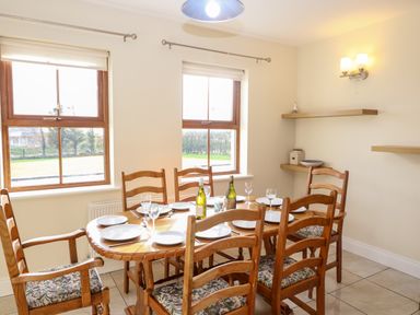 A dining room with wooden table and chairs set with plates and glasses at Ballycahane in Castletownshend County Cork