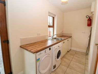A laundry room with washing machine dryer sink countertop and fire extinguisher at Ballycahane Castletownshend County Cork