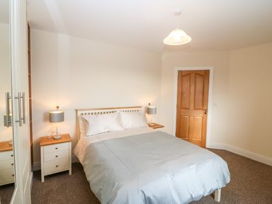 A bedroom with a bed bedside tables lamps and a wooden door at Ballycahane in Castletownshend County Cork