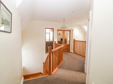 A carpeted hallway with wooden railing and glass door at Ballycahane in Castletownshend County Cork