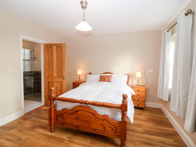 A bedroom with a wooden bed and two bedside tables with lamps at Ballycahane in Castletownshend County Cork