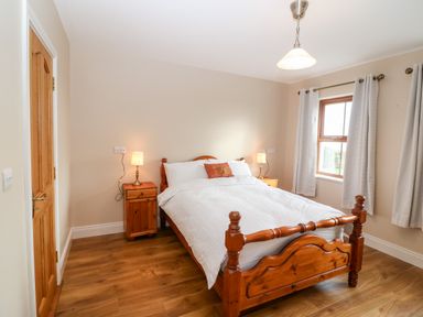 A bedroom with a wooden double bed and two bedside tables with lamps at Ballycahane in Castletownshend County Cork