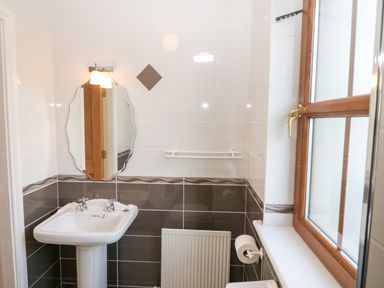 A bathroom with a sink a mirror a window and a radiator at Ballycahane in Castletownshend County Cork