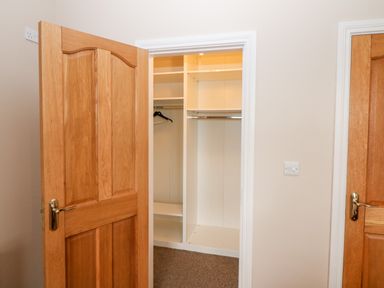 A walk-in closet with wooden doors beige walls and carpet at Ballycahane in Castletownshend County Cork