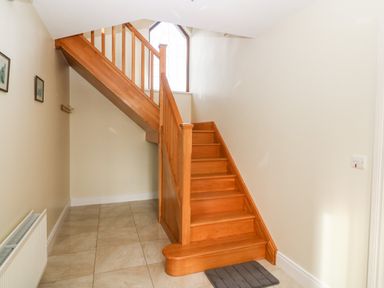A wooden staircase in a hallway with tiled floor and radiator at Ballycahane in Castletownshend County Cork