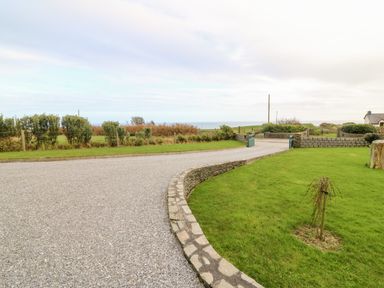 A gravel driveway with a curved stone border and green lawn with small tree at Ballycahane in Castletownshend County Cork