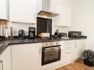 A kitchen with white cabinets a black countertop a built in oven a gas stove a microwave a toaster a coffee maker and a kettle at Stillness Blandford Forum