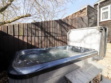 An outdoor hot tub with bubbling water next to a wooden fence and a small wooden step at Stillness in Blandford Forum